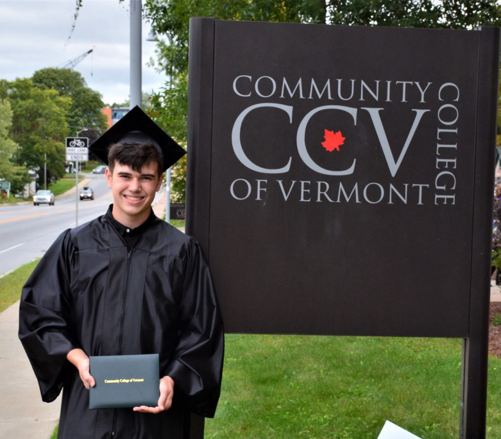 graduate in front of CCV sign