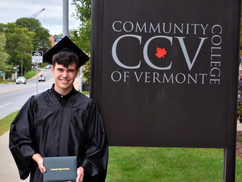 graduate in front of CCV sign